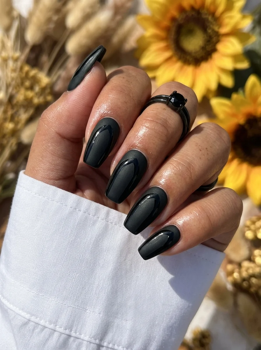 Long coffin nails with a matte black finish and geometric cutout shapes revealing the natural nail underneath.