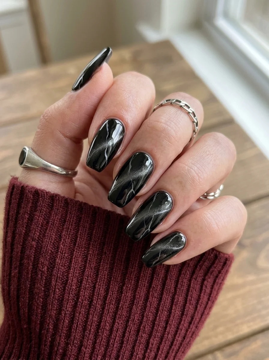 Long coffin nails with a black base and silver-white cat eye diagonal light effect.