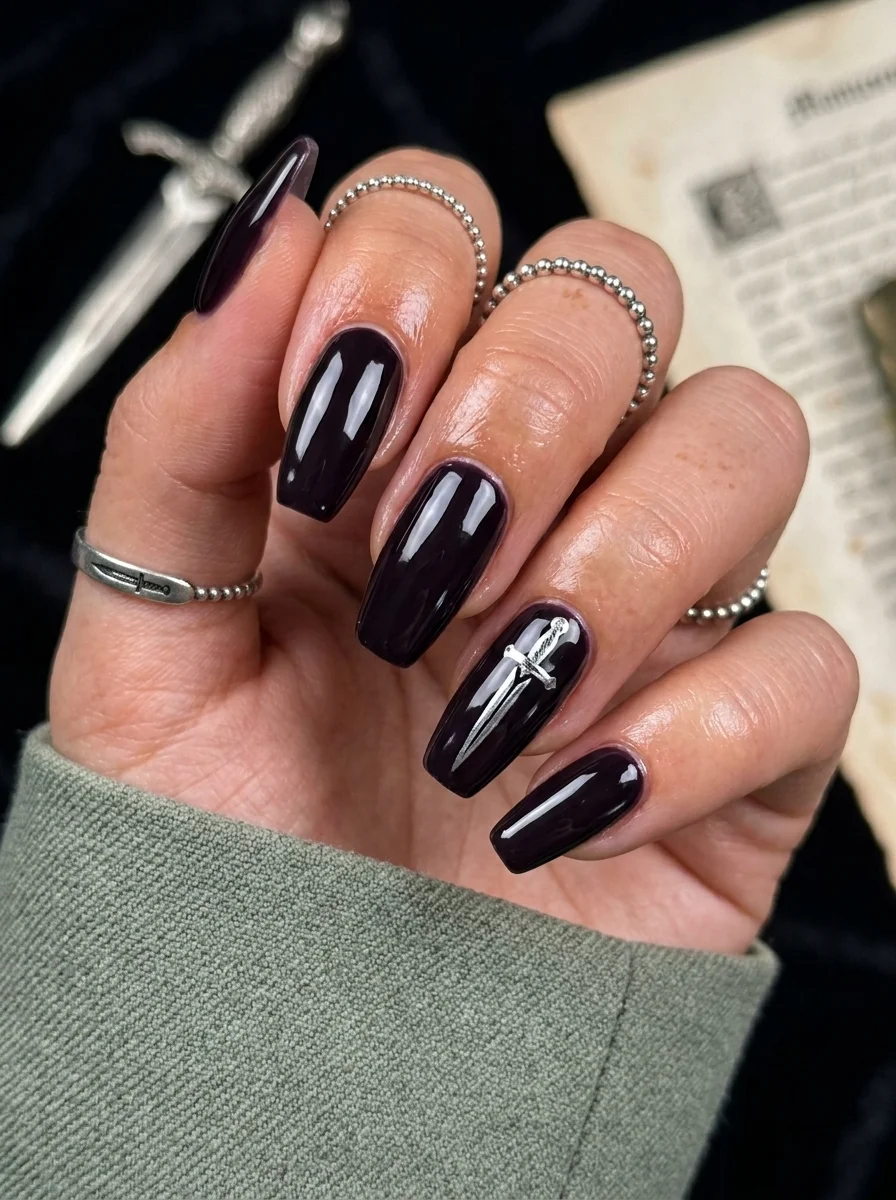 Long coffin nails in deep plum purple with a silver dagger design on one accent nail.