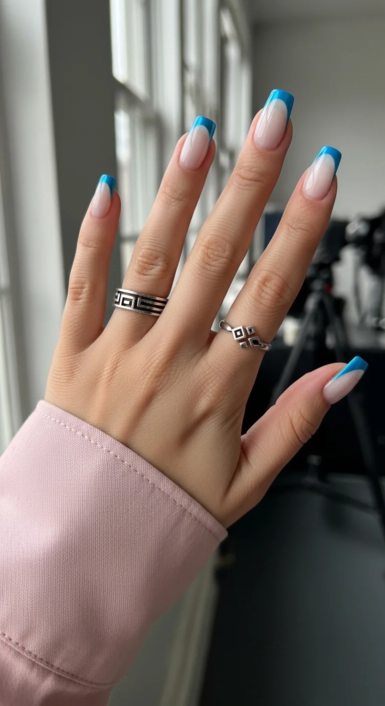 Long square French nails with a nude base and bright sky blue tips.